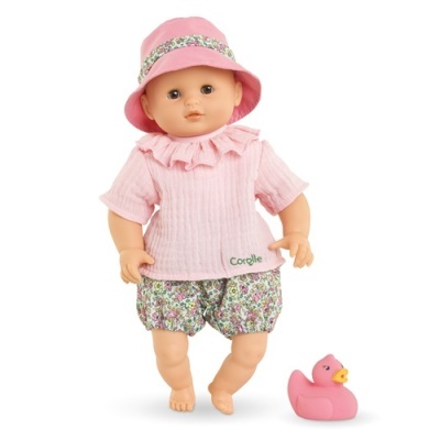 Boneca vestida com roupa rosa e chapéu cor-de-rosa, com patinho de borracha rosa ao lado