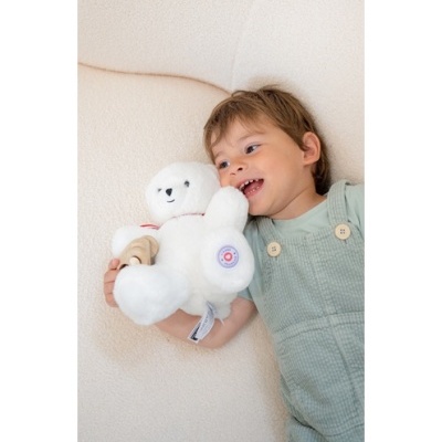 Criança com ursinho de peluche branco num sofá claro