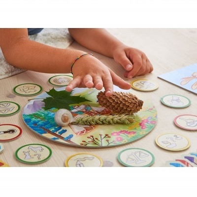 Criança a jogar jogo de tabuleiro com elementos naturais e fichas ilustradas