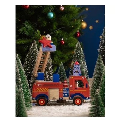 Brinquedo de camião de bombeiros de madeira vermelho com escada, rodeado de árvores de Natal artificiais.