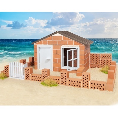 Casa miniatura de tijolos vermelhos com portas e janelas brancas na areia junto ao mar