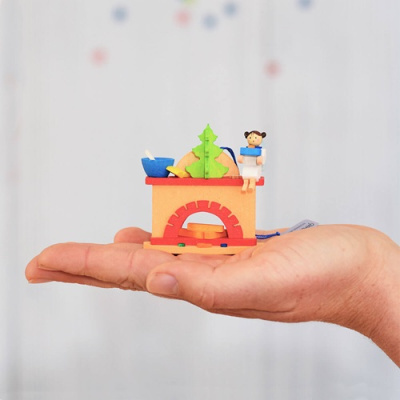 Miniatura colorida de lareira em madeira com figura humana e árvore de Natal