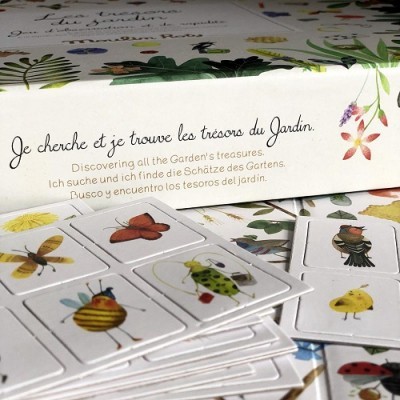 Jogo de cartas com desenhos de insectos e caixa com texto multilingue sobre tesouros do jardim.