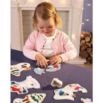 Criança a montar puzzle de madeira colorido, mesa azul, lareira e madeira ao fundo