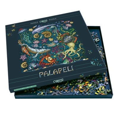 Caixa de quebra-cabeças Palapeli Curiosi com tema marinho e peças espalhadas