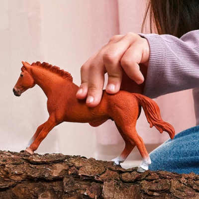 Brinquedo de cavalo castanho com patas brancas em superfície de casca de árvore