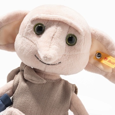 Pelúcia do personagem Dobby com roupa de malha castanha e etiqueta amarela Steiff na orelha