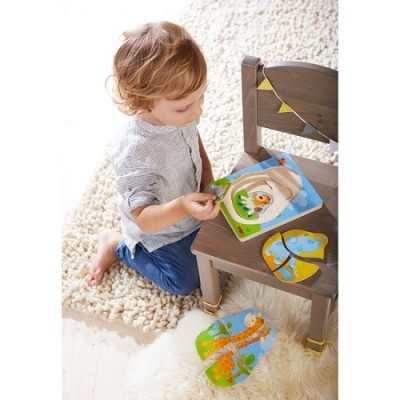 Criança brinca com puzzles de madeira de animais numa cadeira escura com detalhes amarelos