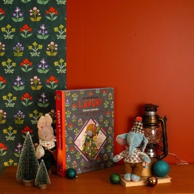 Calendário do advento, peluches, árvore de Natal e bolas decorativas sobre mesa com fundo colorido