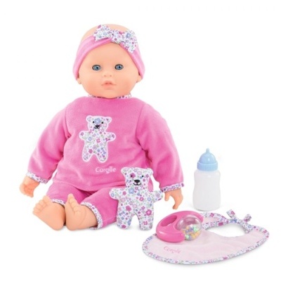 Boneca bebê vestida de cor-de-rosa com acessório e itens complementares, incluindo ursinho, babete, chocalho e mamadeira