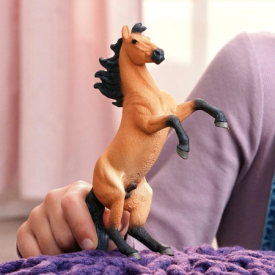Figura de cavalo castanho com crina e patas pretas sobre tecido roxo.