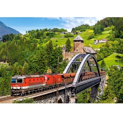 Comboio vermelho a atravessar ponte metálica com paisagem montanhosa verde ao fundo