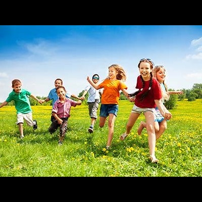 Crianças correndo num campo verde com flores sob céu azul