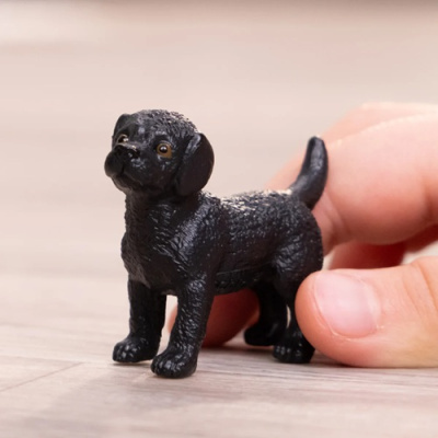 Miniatura de cão preto em madeira clara