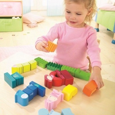 Criança a brincar com blocos de madeira coloridos numa mesa