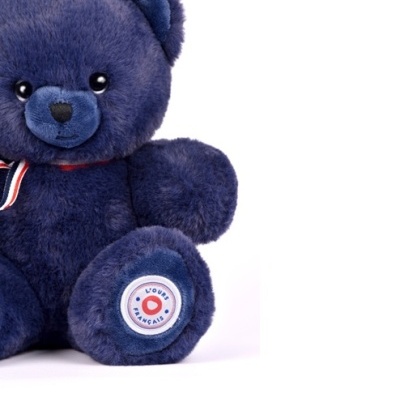 Urso de peluche azul escuro com laço e selo na pata