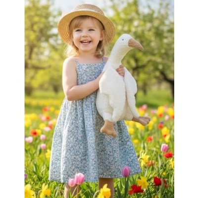 Menina com vestido azul floral e chapéu de palha segurando peluche de ganso em campo florido