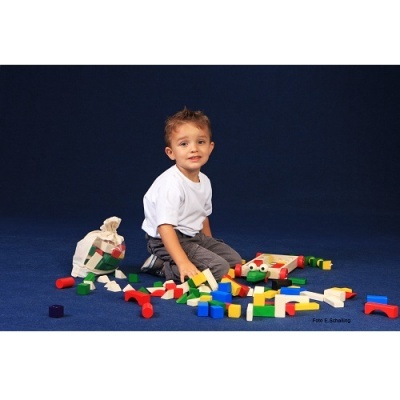 Criança a brincar com blocos de construção coloridos sentada no chão azul