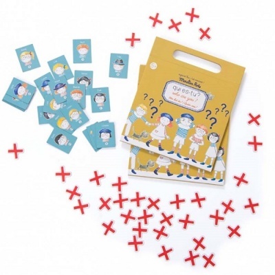 Jogo de cartas 'Que És Tu?' com peças em cruz vermelhas e embalagem amarela com ilustrações de crianças