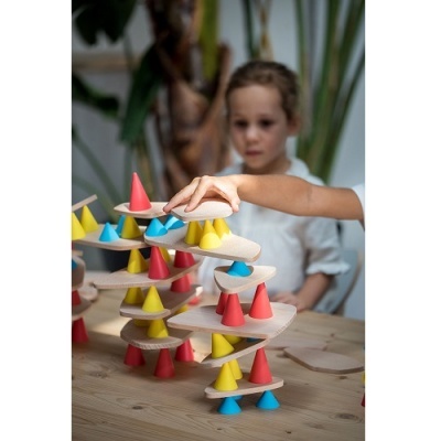Brinquedo de construção em madeira com cones coloridos e criança ao fundo