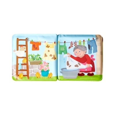 Livro infantil com ilustrações coloridas, senhora a estender roupa, galinha, vaso com flores e gato na escada