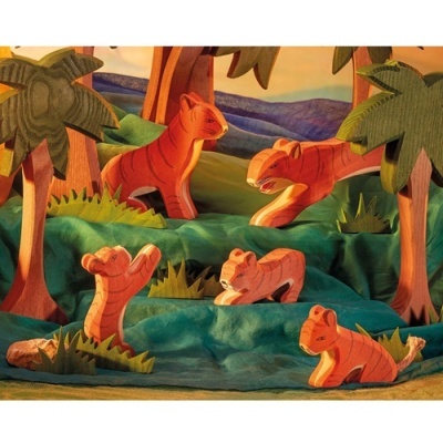 Brinquedos de madeira representando tigres em ambiente natural com árvores e colinas coloridas