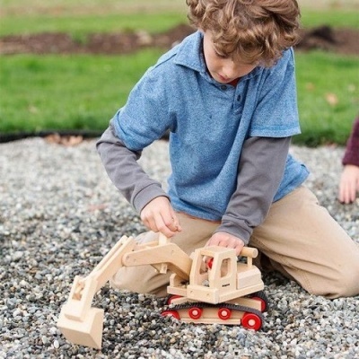 Criança a brincar com escavadora de madeira no chão de cascalho