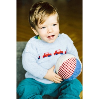 Criança com camisola azul e bola xadrez em tecido.