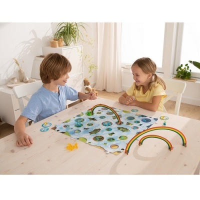 Crianças a jogar jogo de tabuleiro com arcos coloridos numa mesa de madeira