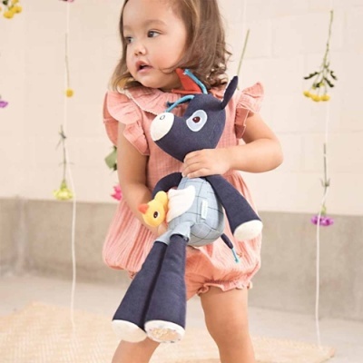 Criança com brinquedo peluche de burro azul e cinzento