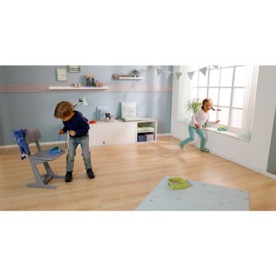 Crianças a brincar em quarto luminoso com cadeira cinza e móvel branco