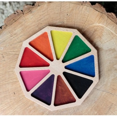 Paleta de madeira colorida com nove cores triangulares sobre tronco de árvore