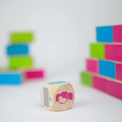 Peça de madeira com rosto de menina rosa com peças coloridas ao fundo