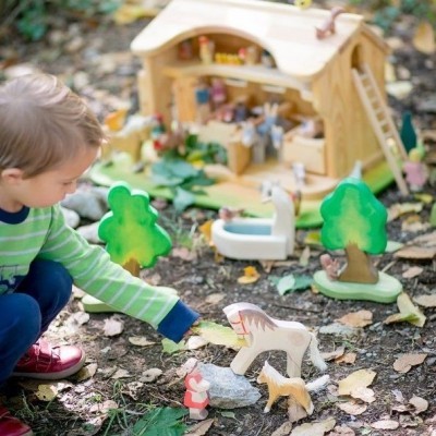 Menino a brincar com brinquedos de madeira ao ar livre