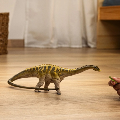 Figura de dinossauro amarelo com tons castanhos no chão de madeira