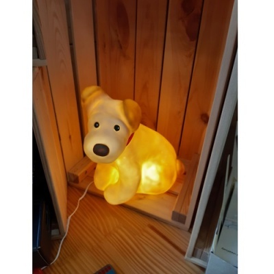Luminária em forma de cão iluminada com luz amarela numa caixa de madeira