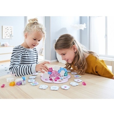 Duas meninas a jogar jogo de tabuleiro colorido numa mesa de madeira clara