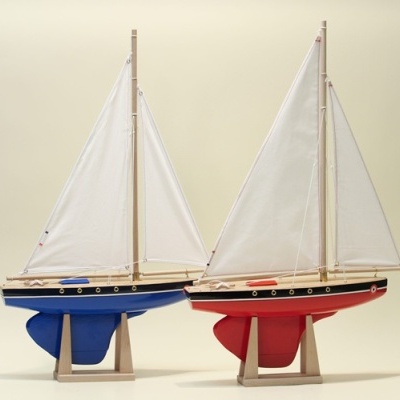 Dois barcos de vela miniatura com velas brancas em fundo neutro