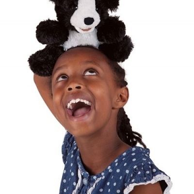 Criança com boneco de pelúcia preto e branco em cima da cabeça