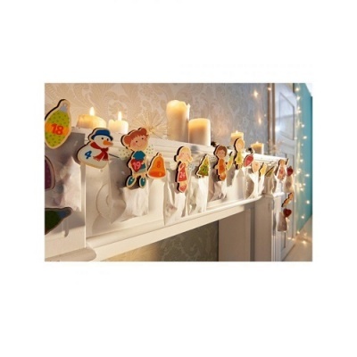 Meia de Natal branca com figuras de madeira numeradas pendurada numa lareira com velas acesas