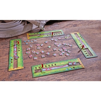 Placas metálicas verdes com pinos vermelhos e peças triangulares coloridas sobre madeira com tubo enrolado ao fundo