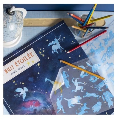 Caderno de constelações azul escuro com lápis coloridos em cima de mesa