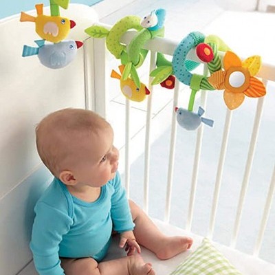 Móbile de berço colorido com pássaros e flores pendurado em berço branco, bebé sentado olhando