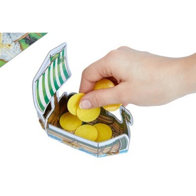 Mão a colocar moedas amarelas de plástico num baú em forma de barco de papel