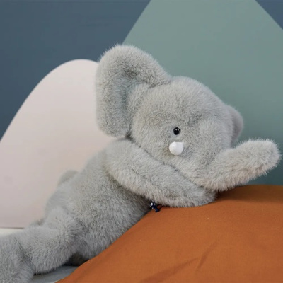 Urso de peluche cinzento suave sobre almofada castanha