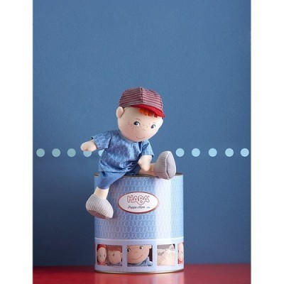 Boneco de peluche infantil com boné vermelho sentado numa lata azul