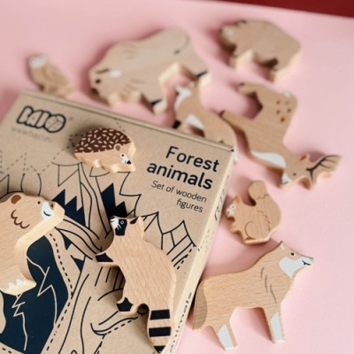 Figuras de madeira de animais da floresta em fundo rosa com caixa de cartão reciclável.