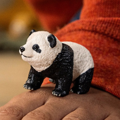 Figura decorativa de panda em preto e branco sobre a mão.
