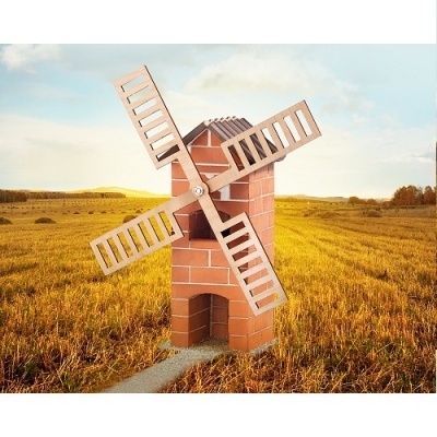 Moinho de vento decorativo em tijolos vermelhos com pás de madeira brancas num campo aberto