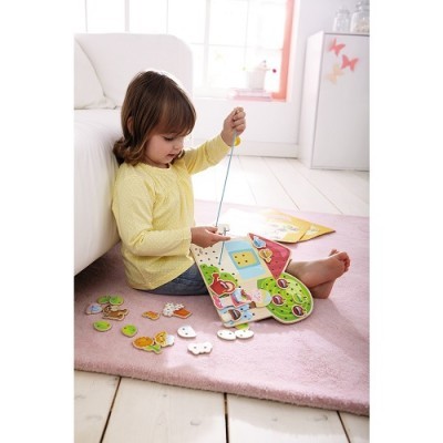 Criança a brincar com brinquedo educativo de madeira num tapete rosa